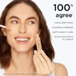 A smiling woman holds Tarte Shape Tape Contour Concealer in shade 20B Light, showcasing the full-size product.