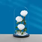 Three preserved white roses displayed in a glass dome, ideal for romantic gifts and elegant home décor.