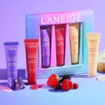 Laneige beauty set featuring On-the-Glow Balm Trio alongside a cupcake and fresh berries on a decorative surface.